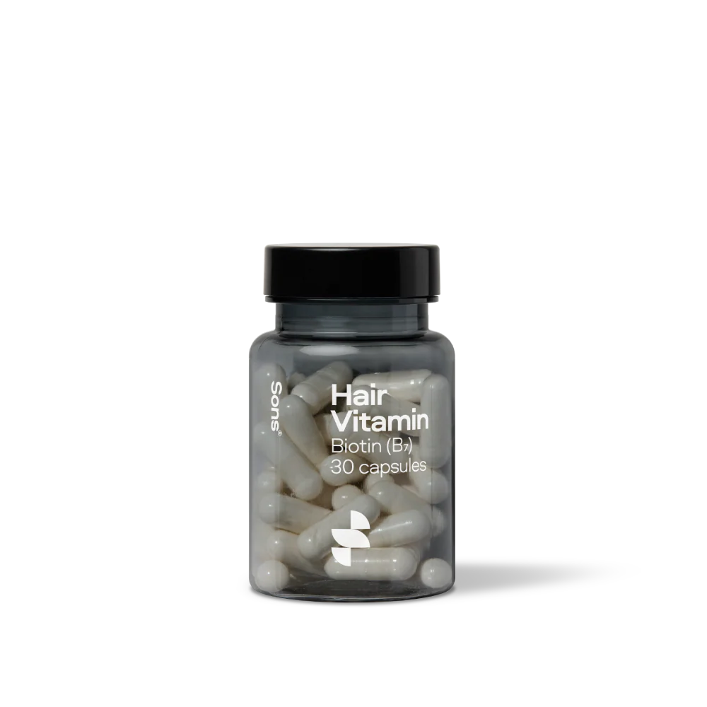 Bottle of hair vitamin capsules on a white background