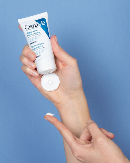 CeraVe hand cream being applied to a hand against a blue background.