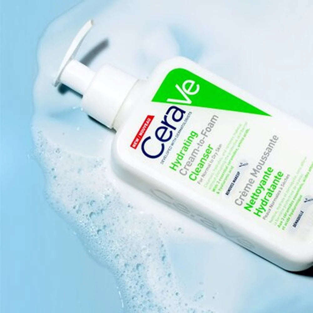 Image of CeraVe Hydrating cream to foam cleanser for normal to dry skin lying on white foam bubbles on a baby blue background.