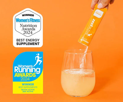 Hand pouring a supplement into a glass with awards for Women's Fitness and Women's Running on an orange background.