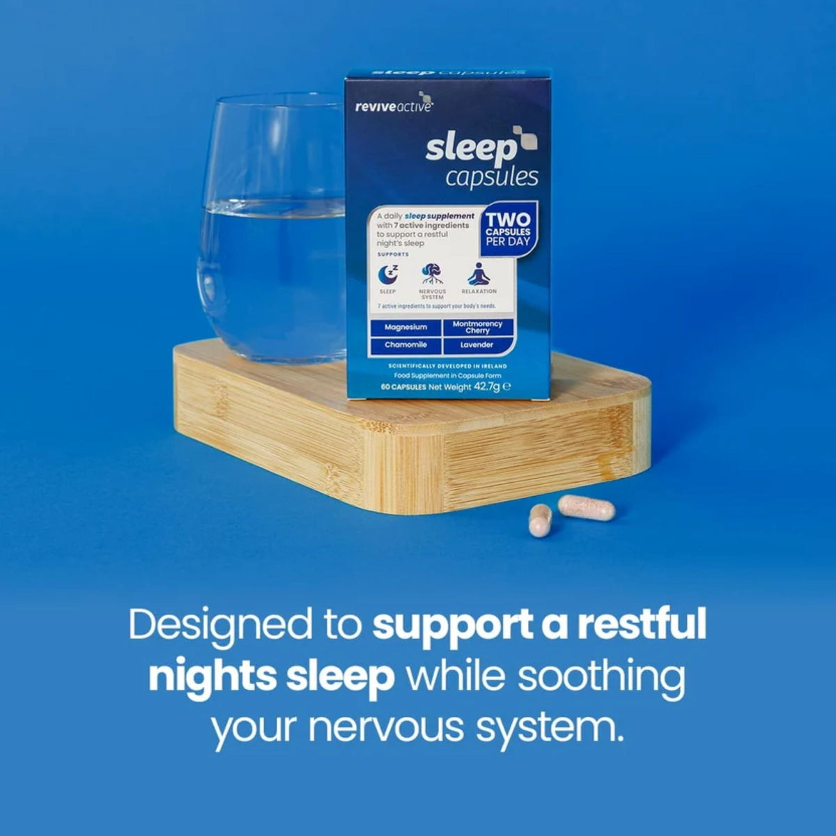 Reviveactive Sleep Capsules packaging box displayed on a wooden block next to a glass of water, with two capsules in front, set against a solid blue background with promotional text.