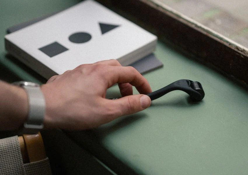 Hand holding a black tool on a green surface with geometric shapes in the background