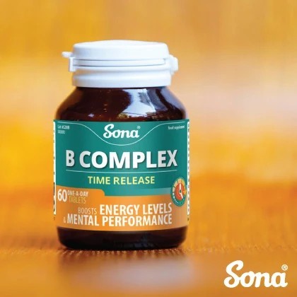 A bottle of Sona B Complex Time Release dietary supplement, featuring a dark amber bottle, white cap, and a green and orange label, set against a warm, blurred orange background.