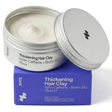 Open jar of thickening hair clay with purple packaging on a white background