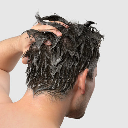 Person with wet, shampooed hair against a plain background