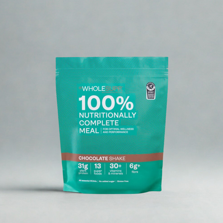 A teal stand-up pouch of Whole Foods 100% Nutritionally Complete Meal in Chocolate Shake flavor, photographed against a neutral light gray background.
WHOLESUPP Chocolate meal replacement pouch, front view.