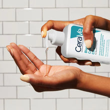 Image of transparent cleanser being dispensed from a pump bottle into the palm of a hand. Background of white tiles behind the scene.
