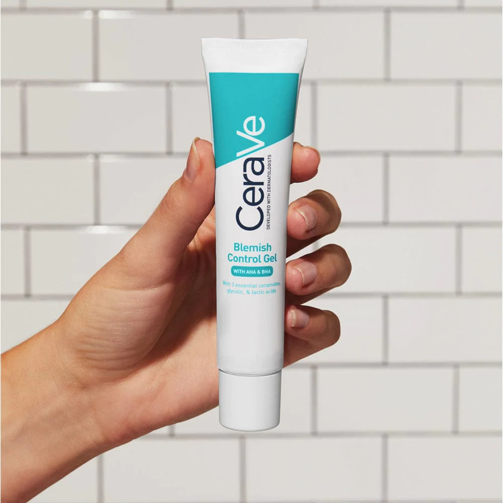 A tube of CeraVe Blemish Control Gel, which is a facial moisturiser for blemish-prone skin being held up against white subway tiles. 