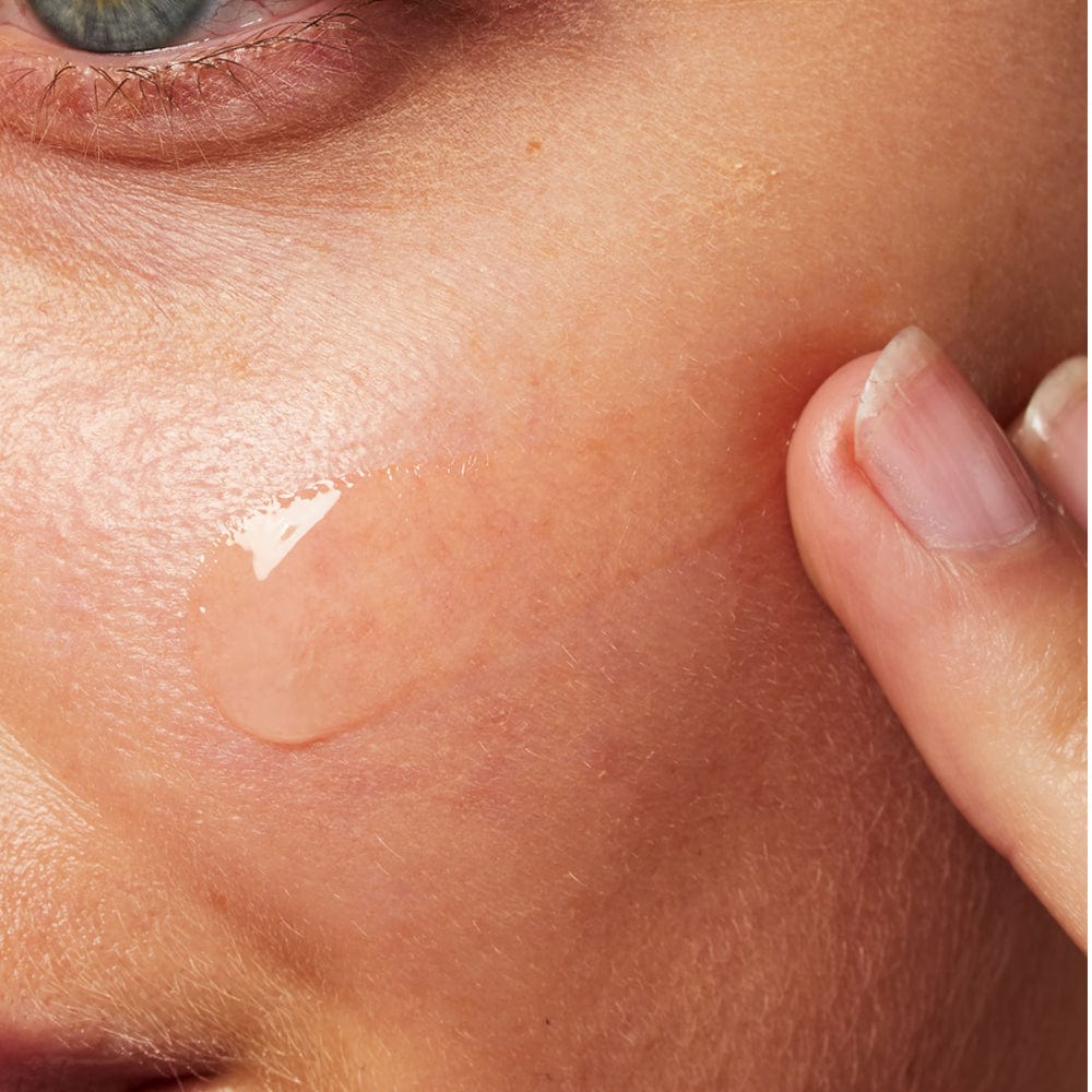 Clear gel being applied to cheek with fingertips.