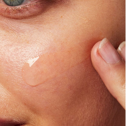 Clear gel being applied to cheek with fingertips.