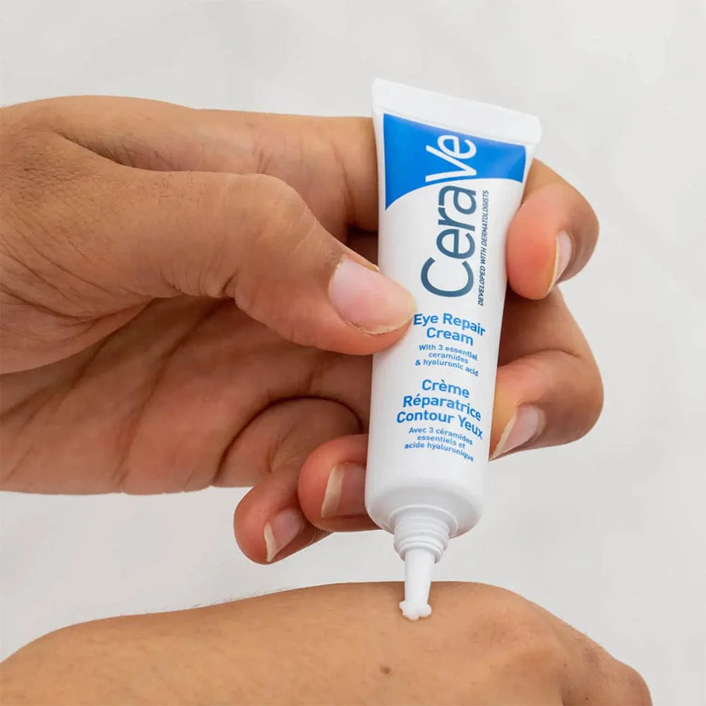 Photograph of blue and white tube of CeraVe Eye Repair Cream being squeezed onto the back of a hand before application.