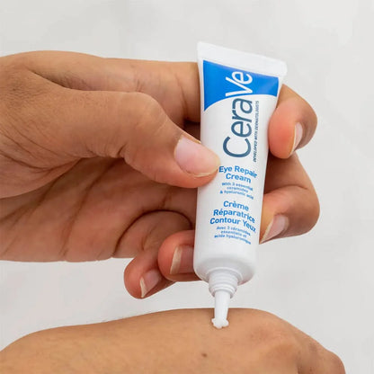 Photograph of blue and white tube of CeraVe Eye Repair Cream being squeezed onto the back of a hand before application.