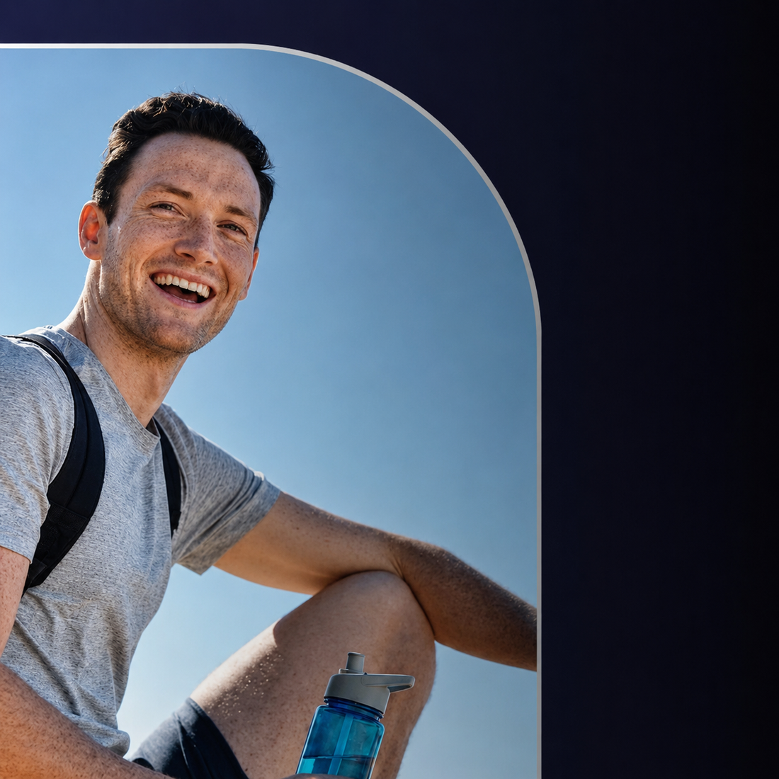 Man with a backpack sitting outdoors with a blue water bottle in the foreground.