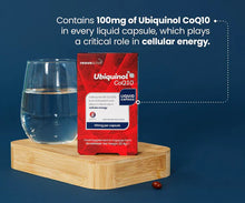 Ubiquinol CoQ10 supplement package with a glass of water on a wooden stand against a blue background.